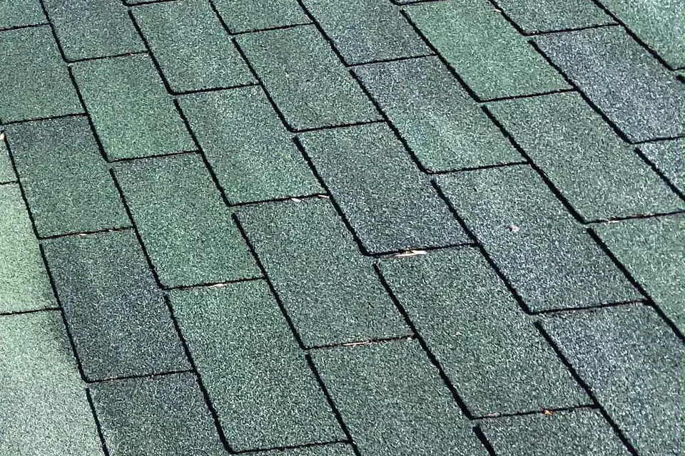 Close-up of the treated shingles on the same roof, darker and evenly colored, cut from the same photo
